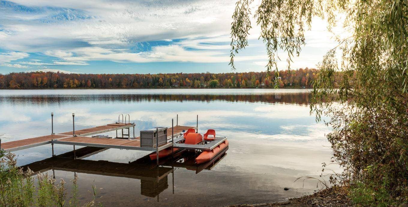 Quai sur un lac calme bordé d'arbres aux couleurs de l'automne